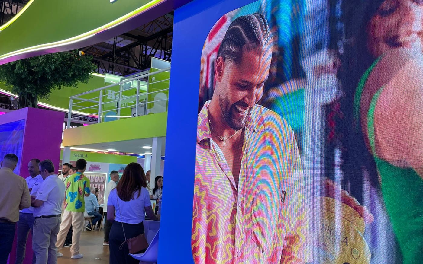 Estande de feira com um painel de LED embutido na cenografia exibindo conteúdo de marca, com visitantes ao lado