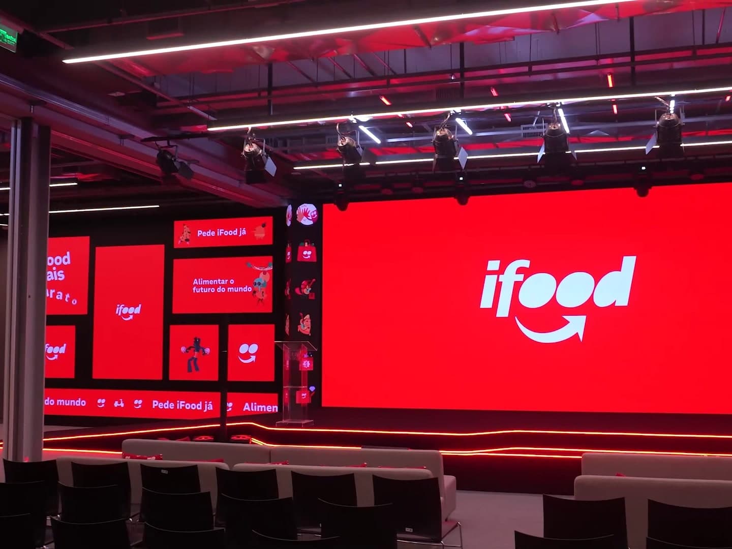 Estúdio do iFood visto da plateia, com painel de LED central, painéis laterais e grid de luz